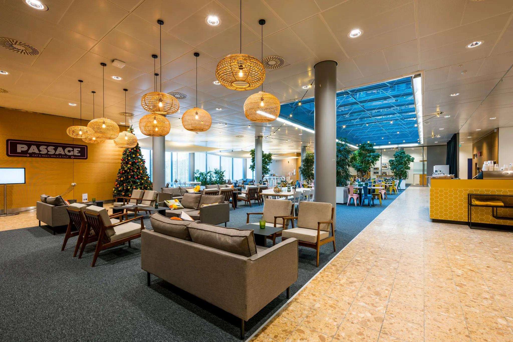 Moderne en sfeervolle lounge- en eetruimte in Passage aan de Burgemeester Rijnderslaan, met zithoeken, kerstboom en kleurrijke eetgedeelte.